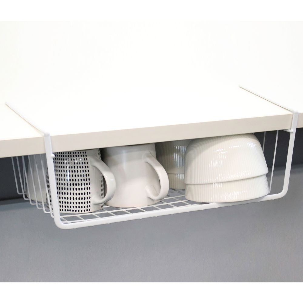 White wire basket mounted under a shelf holding mugs and stacked bowls.